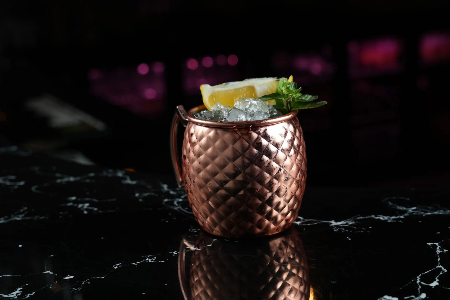 Ein Cocktail im Kupferbecher mit Eis auf einem Bartresen