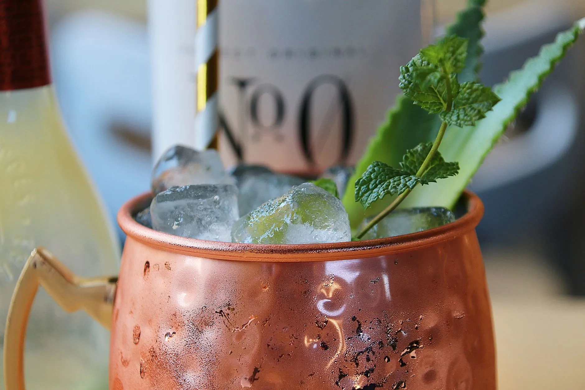 Ein kalter Cocktail im Kupferbecher mit Eis, Minze und Strohhalm
