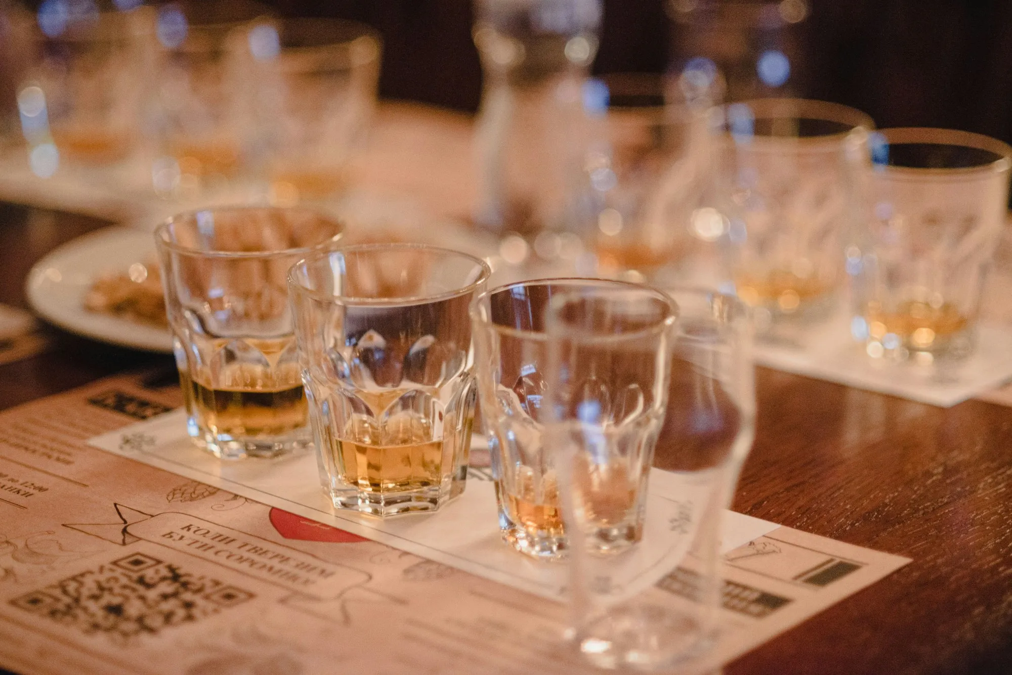Mehrere gefüllte Whiskygläser auf einem Holztisch