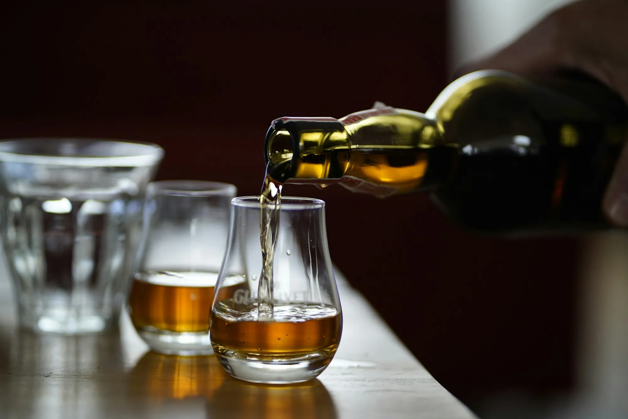 Eine Person hält eine Whiskyflasche an einer Bar