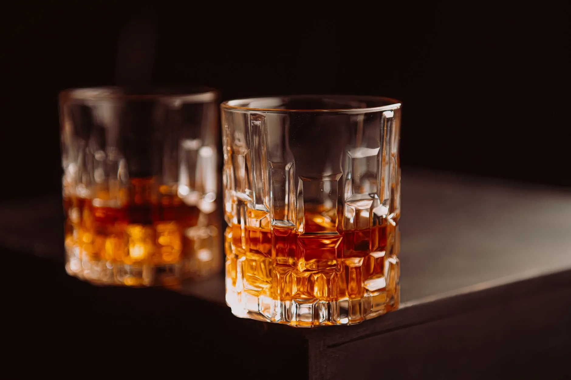 Kristallgläser mit Whisky auf dunklem Holz