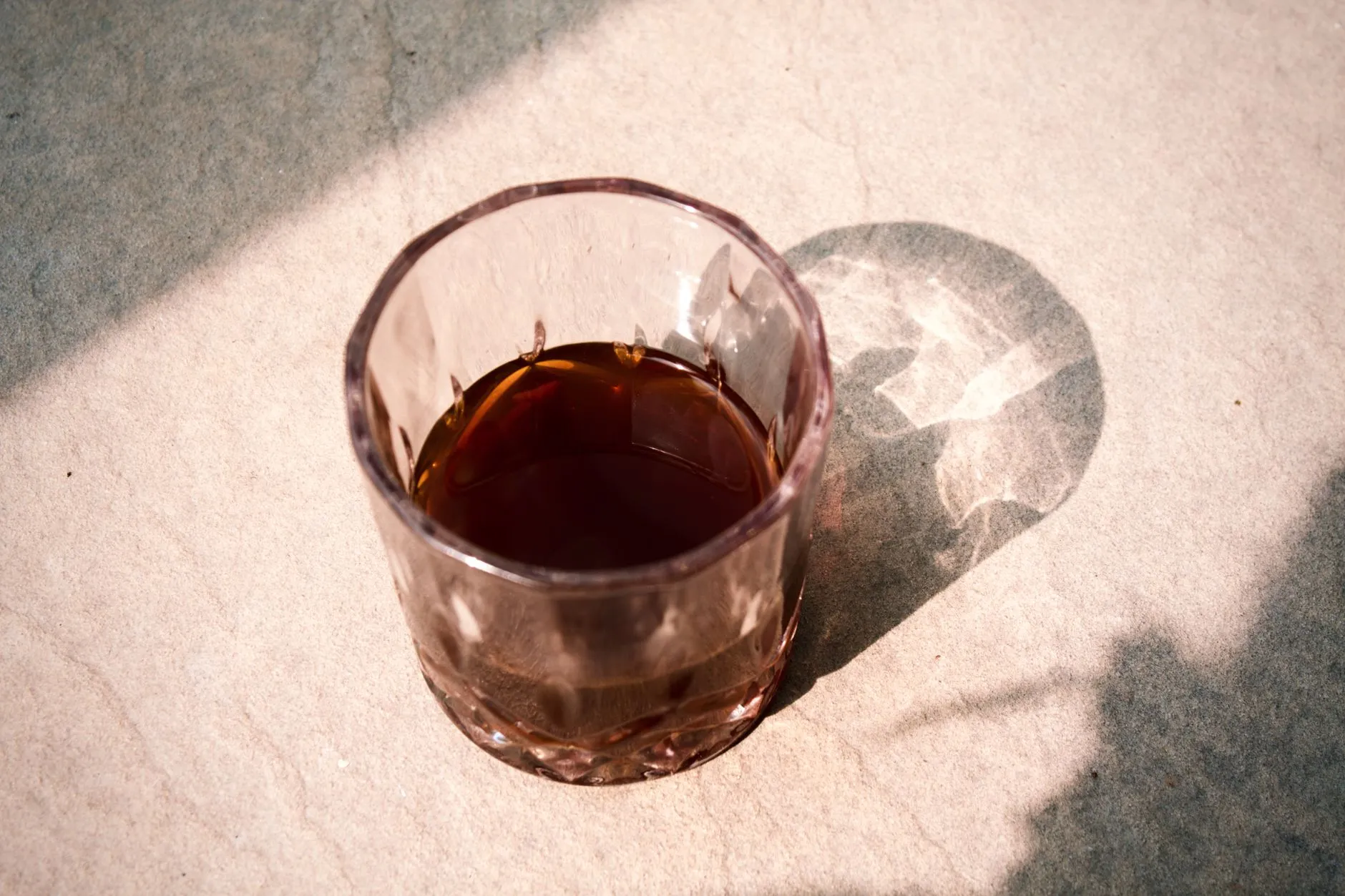 Ein Glas mit braunem Getränk im Sonnenlicht