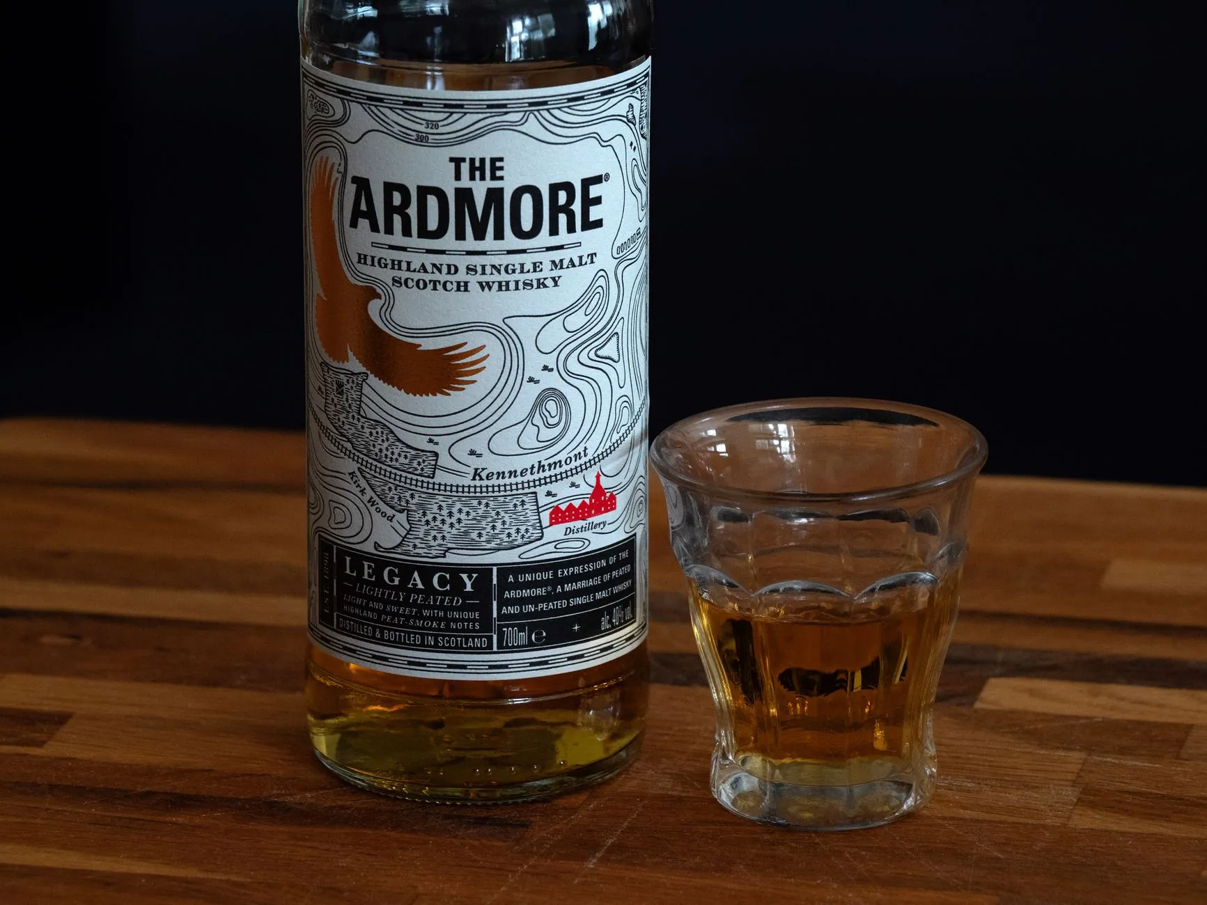 Eine Flasche Single Malt Whisky mit Glas auf einem Holztisch