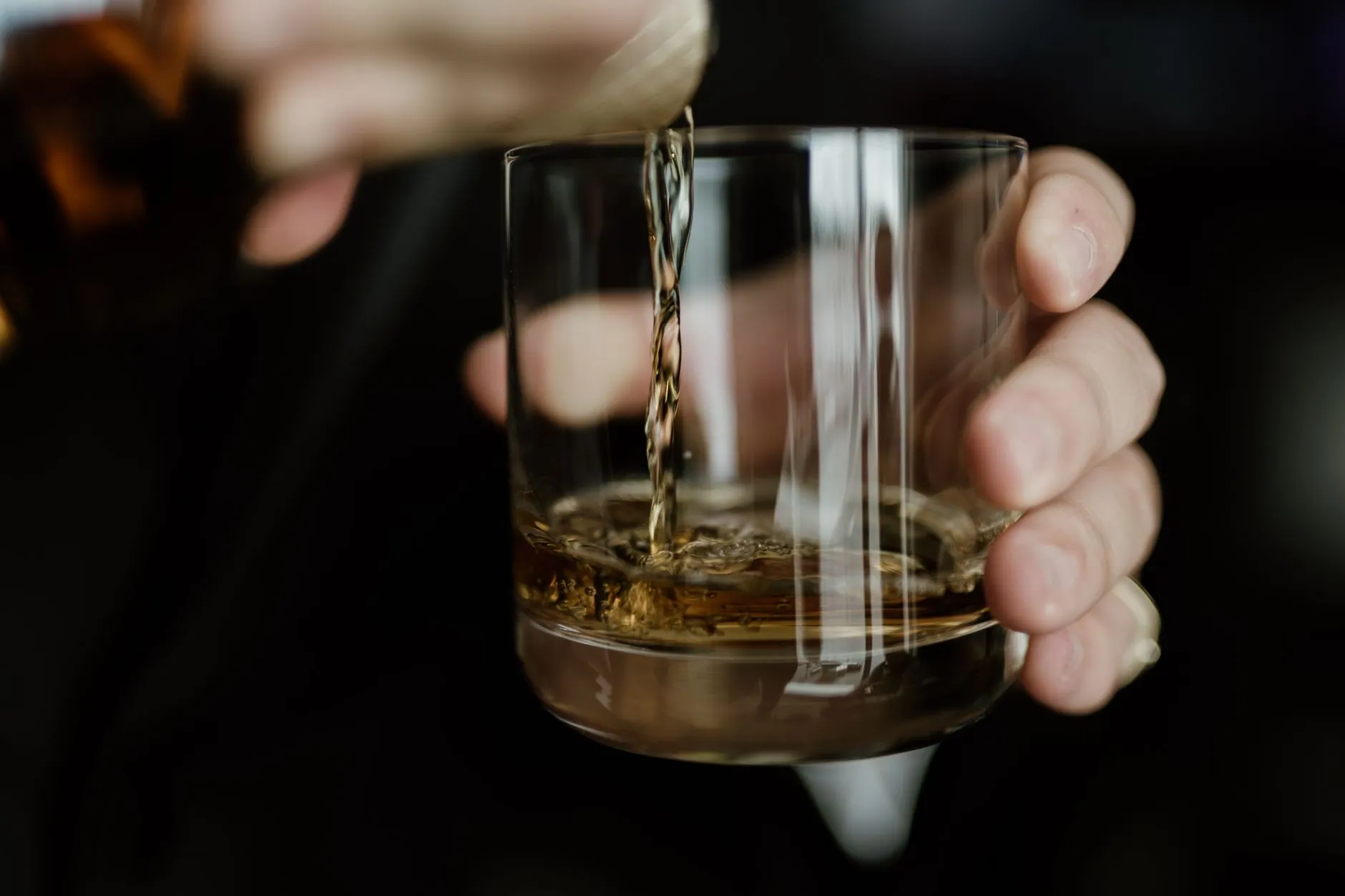 Whisky wird aus einer Flasche in ein Glas gegossen